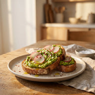 Zwei Scheiben geröstetes Bauernbrot mit grob zerdrückter Avocado, Radieschenscheiben, Chiliflocken und weißen Salzperlen