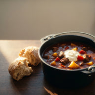 Dunkelrote Gulaschsuppe mit Rindfleisch und Paprika in einem gusseisernen Topf