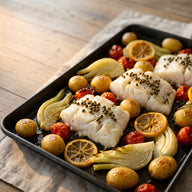 Weiße Kabeljaufilets auf geröstetem Fenchel, Kirschtomaten und Kartoffeln auf einem Backblech