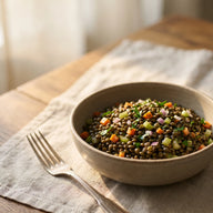 Eine Schale mit lauwarmem Linsensalat aus dunklen Linsen, Möhrenwürfeln, Sellerie und Petersilie