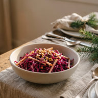 Eine Schale mit fein geschnittenem violettem Rotkohlsalat, Apfelstücken und gerösteten Haselnüssen