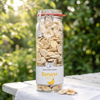 Großes Bügelglas gefriergetrocknete Bananen von Genusspower auf einem weißen Gartentisch im Morgenlicht