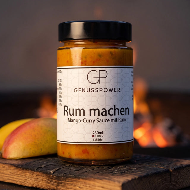 Rum machen Mango-Curry Sauce im Glas auf verkohlter Eiche, daneben eine aufgeschnittene Mango