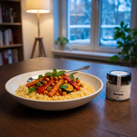 Couscous mit Ofengemüse in einer Keramikschale am Esstisch an einem Winterabend, daneben Harissa von Genusspower