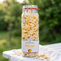 Großes Bügelglas gefriergetrocknete Mango von Genusspower auf einem weißen Gartentisch im Morgenlicht