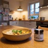 Hähnchencurry mit Reis in einer Keramikschale in einer Familienküche am Sonntagabend, daneben Mühlen Curry von Genusspower