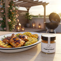 Gegrillte Hähnchenschenkel mit Ananas und Mango auf einer Terrasse am Sommerabend, daneben Tropical Island von Genusspower
