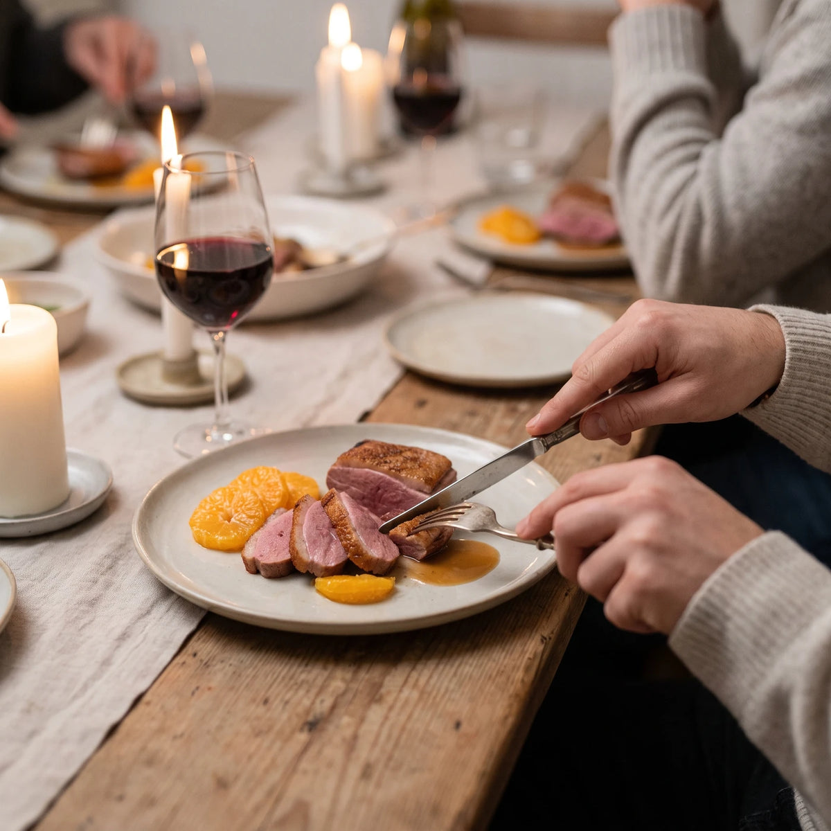 Geschnittene Entenbrust mit Mandarinenfilets bei Kerzenlicht am Abendtisch