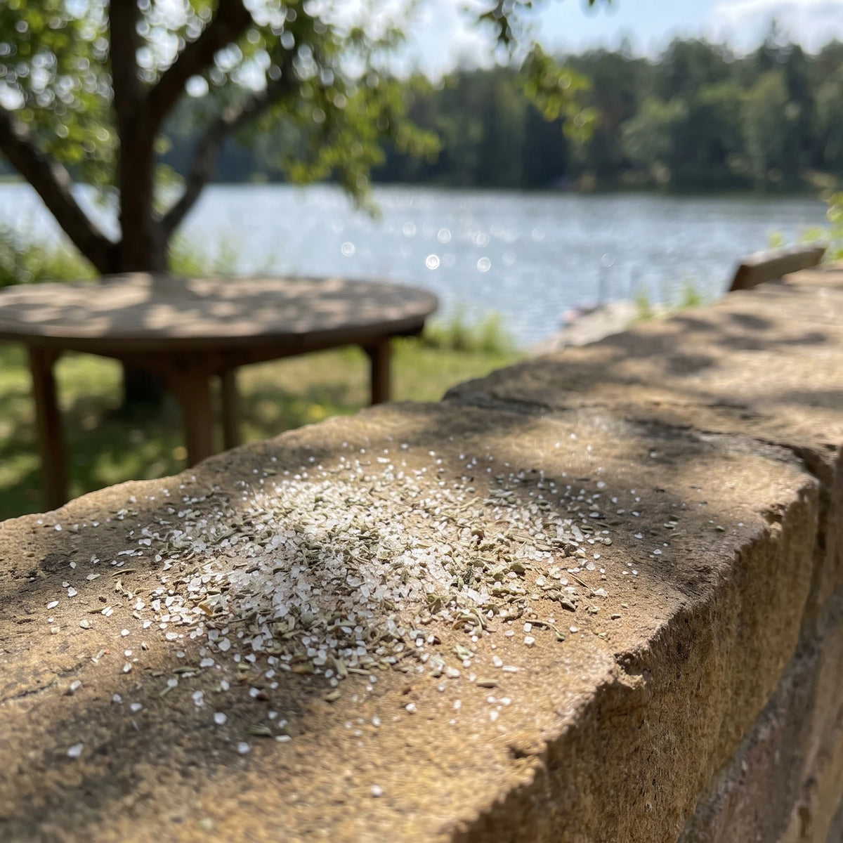 Kleiner Haufen weißes Salz mit grünen Kräutern auf einer warmen Steinmauer im Garten