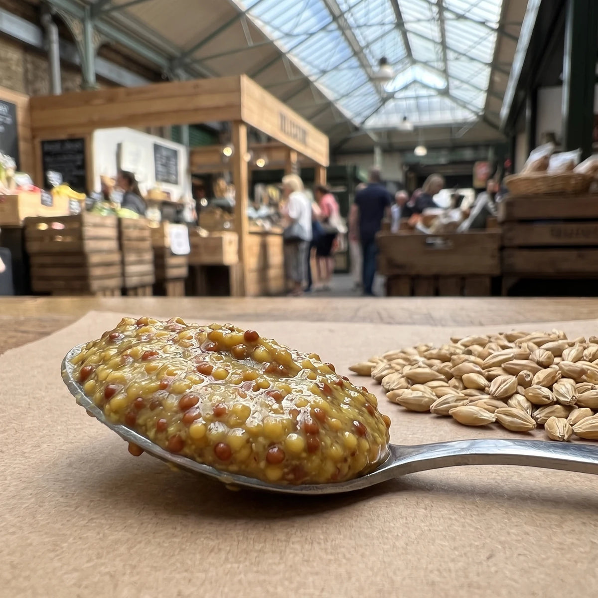 Löffel mit grobkörnigem Bier Senf, daneben Malzkörner auf Kraftpapier