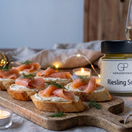 Geröstete Baguettescheiben mit heller Creme, Räucherlachs und Dill auf einem Holzbrett