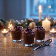 Gläser mit dunkler Schokoladenmousse, darauf zerbröselte dunkelviolette Brombeeren