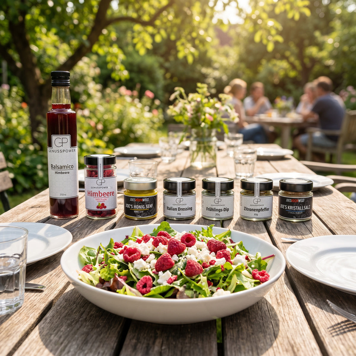 Angemacht: Balsamico Himbeere und sechs Gläser in einer Reihe auf einem Gartentisch im Sommer, davor eine Schüssel Salat mit Himbeeren und Feta