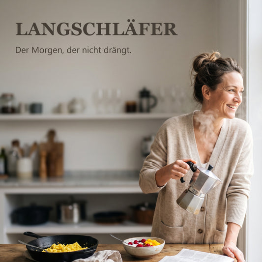 Langschläfer – Frau am Küchenfenster gießt Kaffee auf, Rührei und Joghurtschale auf dem Tisch
