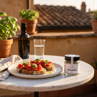Bruschetta mit Tomaten und Basilikum auf einem Keramikteller auf einer Dachterrasse in Rom, daneben Bruschetta von Genusspower