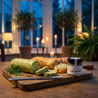 Selbstgemachte Kräuterbutter mit Baguette auf einem Holzbrett in einem Wintergarten bei Kerzenlicht, daneben Cafe de Paris von Genusspower