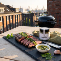 Gegrilltes Flanksteak mit grüner Sauce auf Schiefer auf einem Balkon über Hamburg, daneben Chimichurri von Genusspower