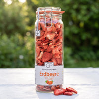 Großes Bügelglas gefriergetrocknete Erdbeeren von Genusspower auf einem weißen Gartentisch im Morgenlicht