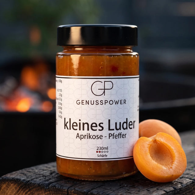 kleines Luder Grillsauce im Glas auf verkohlter Eiche, daneben eine halbe Aprikose