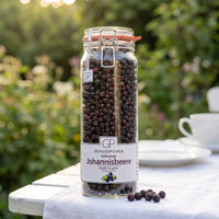 Großes Bügelglas gefriergetrocknete Johannisbeeren von Genusspower auf einem weißen Gartentisch im Morgenlicht
