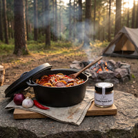 Schichtfleisch im Dutch Oven am Lagerfeuer auf einer Waldlichtung, daneben Smoky Dutch Oven von Genusspower