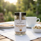 Kleines Glas gefriergetrocknete Stachelbeere von Genusspower auf einem Gartentisch, daneben Kaffeetasse und Schale