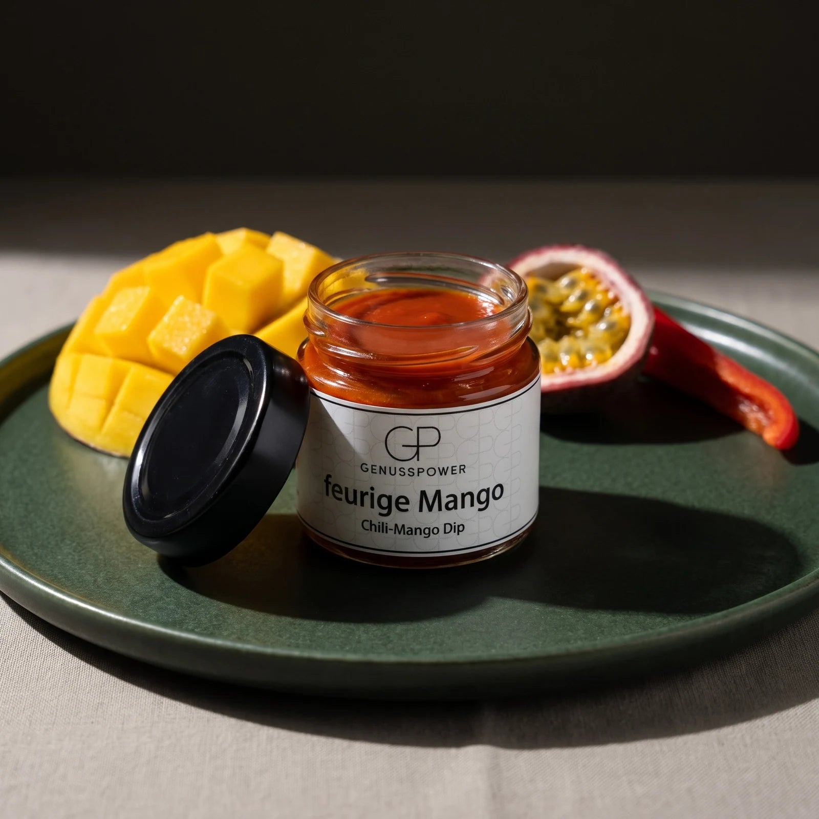 Offenes Glas Feurige Mango auf tiefgrüner Glasur